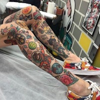 a man with tattoos on his leg sitting on a chair